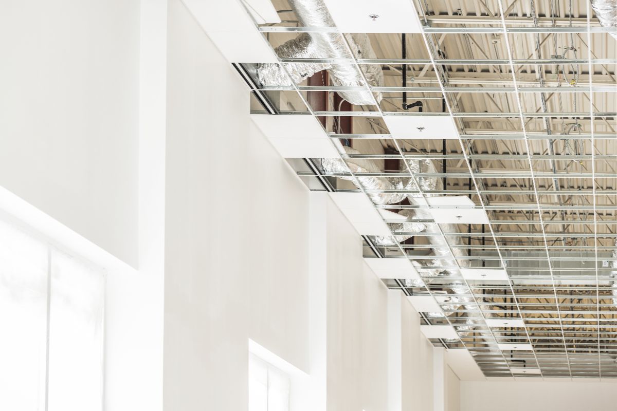 White PVC ceiling tiles being installed in an office space with a high ceiling