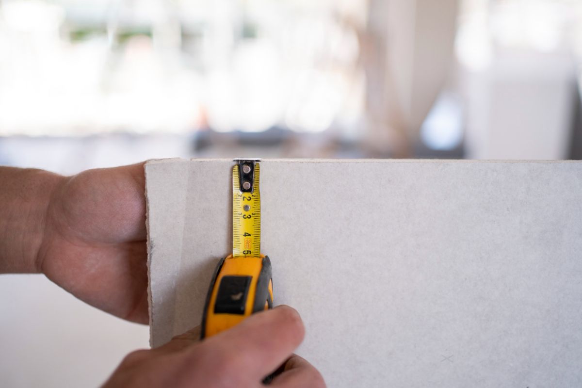 A gysum board being measured for thickness